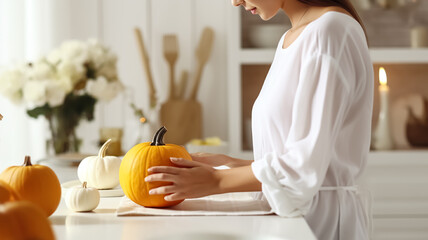 A girl in white clothes puts a pumpkin on the table. Thanksgiving background.