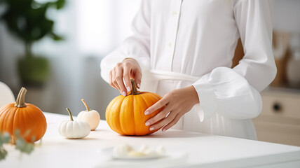 A girl in white clothes puts a pumpkin on the table. Thanksgiving background.