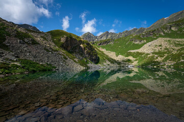 View of the Dukka lake "Rybka" on the Malaya Dukka River on the slopes of the Arkasar ridge in the North Caucasus on a sunny summer day, Arkhyz, Karachay-Cherkessia, Russia © Ula Ulachka