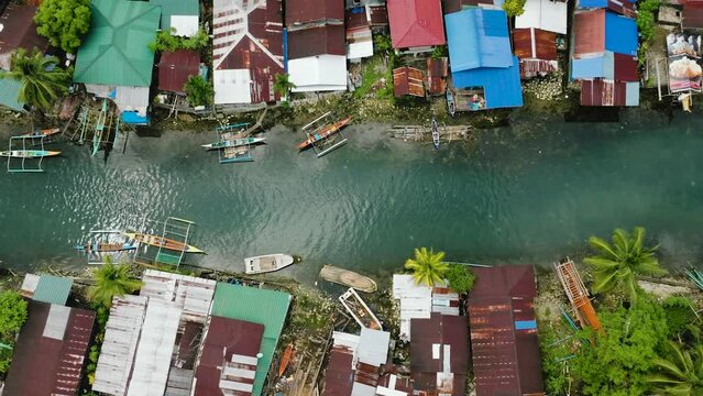 Top view of fishermans villages and transparent turquoise cold spring river with boats. Surigao del Sur, Philippines.