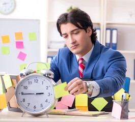 Young male handsome employee in conflicting priorities concept