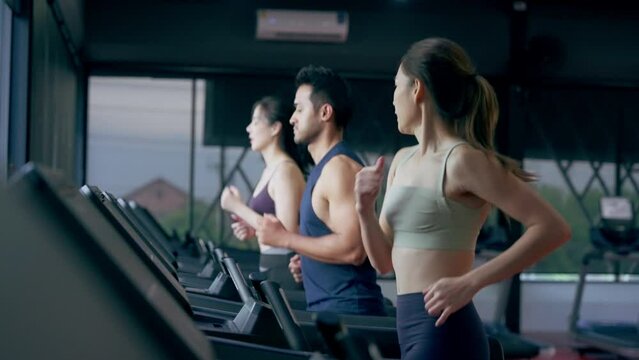 Fit young woman and man running on a treadmill during a workout class at fitness gym