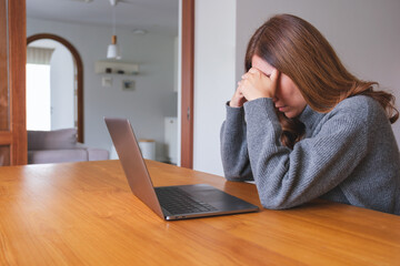A woman get headache and stressed while working online on laptop computer at home