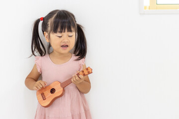 オモチャのギターを弾く女の子のイメージ（3歳、日本人）