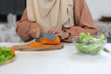 healthy food, weight loss concept beautiful asian muslim woman Attractive woman in headscarf prepares delicious food at kitchen, chopping carrots to nourish skin health care concept