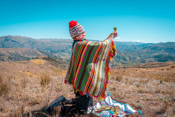 Hombre de tierra con ropa típica haciendo el Kinto a pacha mama o tierra del sol.   - obrazy, fototapety, plakaty