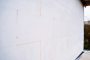 The outer part of the wall of the house is pasted over with white foam plastic close-up - obrazy, fototapety, plakaty