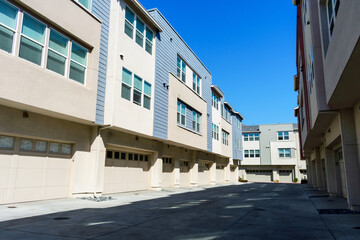 Exterior view of row of garage doors and low rise residential units in parking area for modern...
