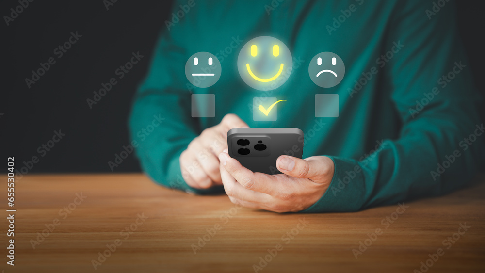 Leinwandbilder user hand using a mobile phone with pop up smile face icon for feedback review satisfaction service 