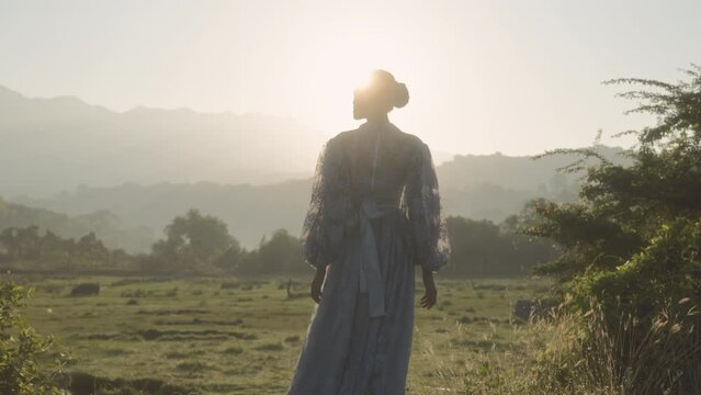 Woman In Grassy Field Against Early Morning Mountains