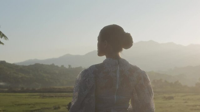 Woman During First Dawn In Grassy Field With Mountains