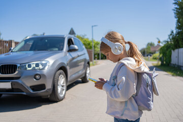 Girl with headphones and cellphone crossing the road, not looking at car let