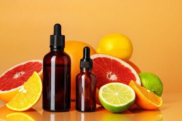 Glass bottle with essential citrus oil on orange background