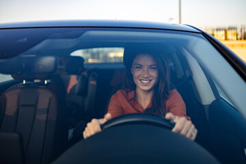 Happy woman driving a car and smiling. Cute young success happy brunette woman is driving a car....