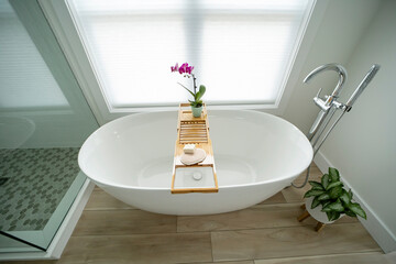 Elegant modern white freestanding bathtub with a tray