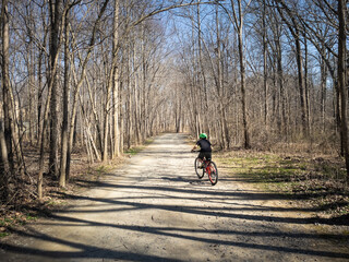 Young boy riding bicycle on path in early spring.