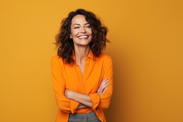 40 - year - old woman wearing a bright clothes next to a orange background. Beautiful businesswoman, who is smiling and laughing at isolated background. - obrazy, fototapety, plakaty