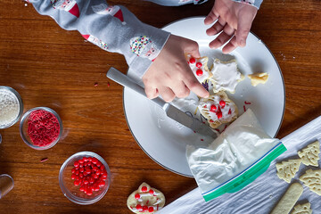 Overhead view of boy's hands as they decorate a Christmas cookie.