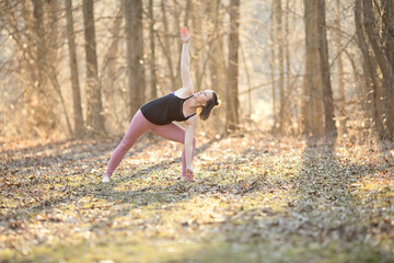 Fototapeta premium Triangle yoga pose; woman practicing yoga outside