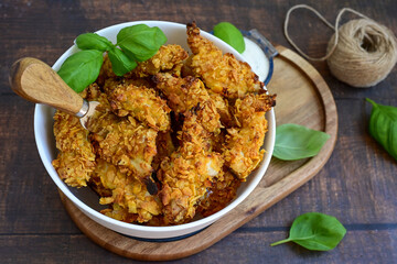 
 Crispy  deep fried   chicken strips and wedges potato. Breaded  with cornflakes chicken  breast fillets  with chilly peppers and fresh   basil on wooden rustic background