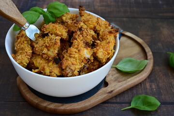 
 Crispy  deep fried   chicken strips and wedges potato. Breaded  with cornflakes chicken  breast fillets  with chilly peppers and fresh   basil on wooden rustic background