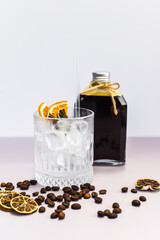 Cold brew coffee in a bottle with transparent glass full of ice on light gray background