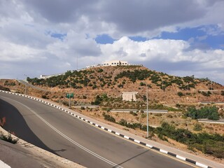 Beautiful daytime sky view of Al Bahah city in Saudi Arabia. City buildings, hills and clouds are visible in the background.