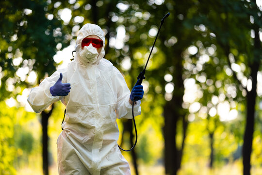 A worker in special clothing for working with pesticides in an outdoor park. Pest control, insect disinfestation