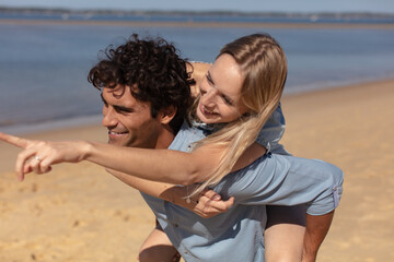 guy carrying a girl on his back at the beach