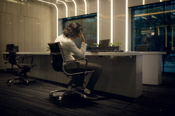 Side view of young businessman sitting at desk in office and looking away, Business disappointment...