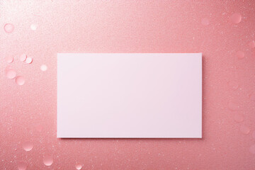 A mock-up of a white postcard lies on a pink table with sequins and rhinestones