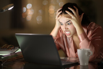 Angry tele worker working with laptop in the night - 655588027