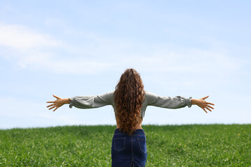Happy woman celebrating outstretching atms in a field