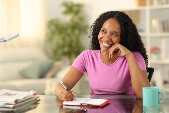 Happy Black Woman Writing In Agenda Dreaming