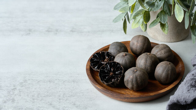 black dry persian lime loomi amani in wood plate on white table background. black dry persian lime loomi amani on white table. black dry persian lime loomi amani on white food table background.
