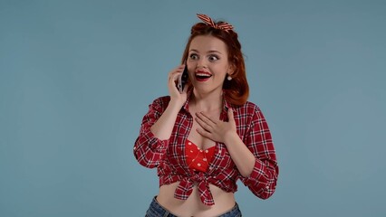 In the frame on a blue background young red-haired woman with bright makeup. She happily and...
