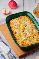 Kugel, a casserole of noodles, cottage cheese, apples and raisins in a green ceramic form on a...