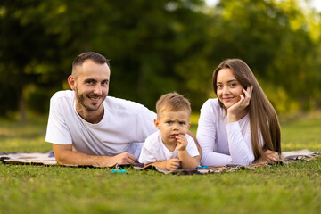 Fototapeta premium Happy family with little son on summer picnic in park