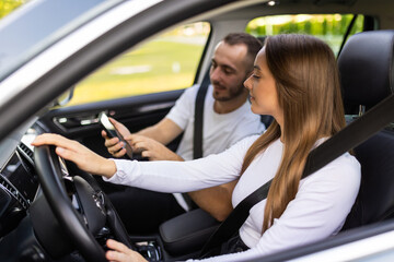 Fototapeta na wymiar Couple driving and using phone in car enjoying road trip
