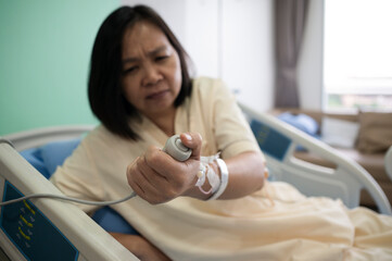 Middle-aged Asian female patient recovering from illness in hospital room, health care concept.