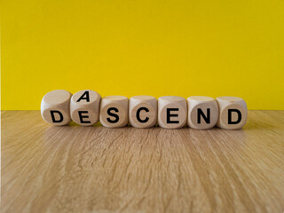 Ascend or descend symbol. Concept words Ascend and Descend on wooden cubes. Beautiful wooden table...