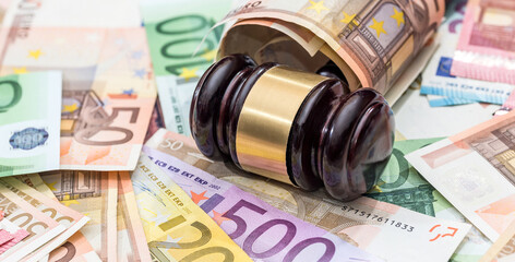 financial judgment with wooden judge's hammer and stack of eu euro banknotes