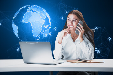Attractive young european businesswoman at desktop using laptop and cellphone with glowing polygonal globe hologram with icons on blurry background. Global technology and communication concept.