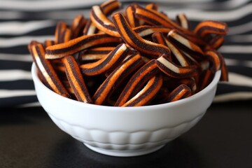black and orange striped licorice twists in a white bowl - Powered by Adobe