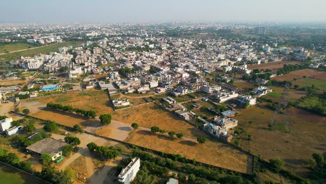 Descending aerial drone shot showing cluttered small houses and empty fields stretching into the distance showing smaller cities like jaipur, indore, gurgaon, hyderabad,