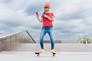 Portrait Of Skater Girl In Skatepark. Female Teenager In Casual Outfit standing On Skateboard on...