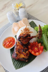 spicy chicken roasted with hot rice and raw vegetables,cucumbar,tomato, served on banana leaf