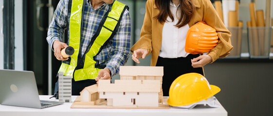 Two colleagues discussing data working and tablet, laptop with on architectural project at construction site at desk in modern office