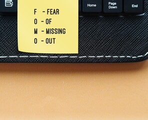 On copy space background, stick note on laptop with text FOMO - FEAR OF MISSING OUT, fear feeling...