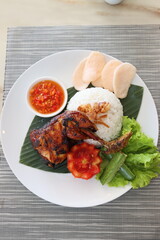 spicy chicken roasted with hot rice and raw vegetables,cucumbar,tomato, served on banana leaf